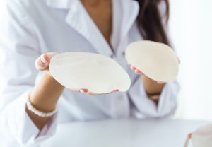 woman holding 2 breast implants
