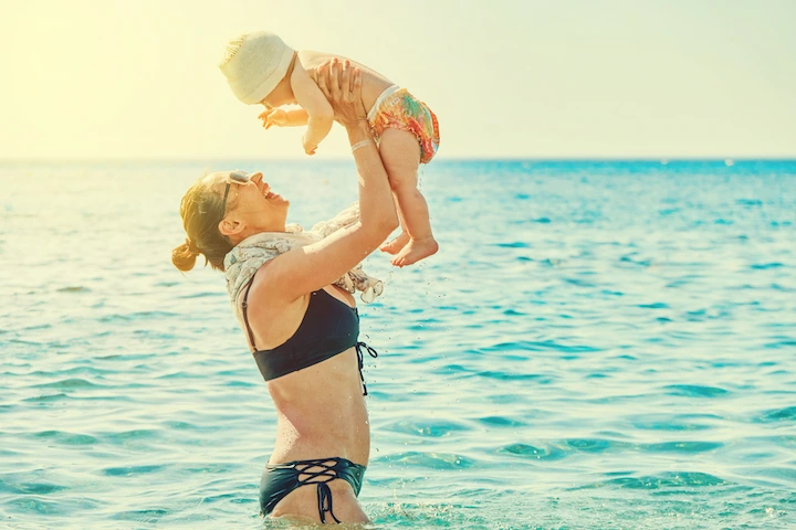 Happy mom holding her young child on the beach