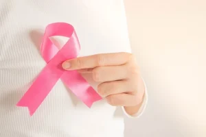 Woman holding the pink ribbon over her heart