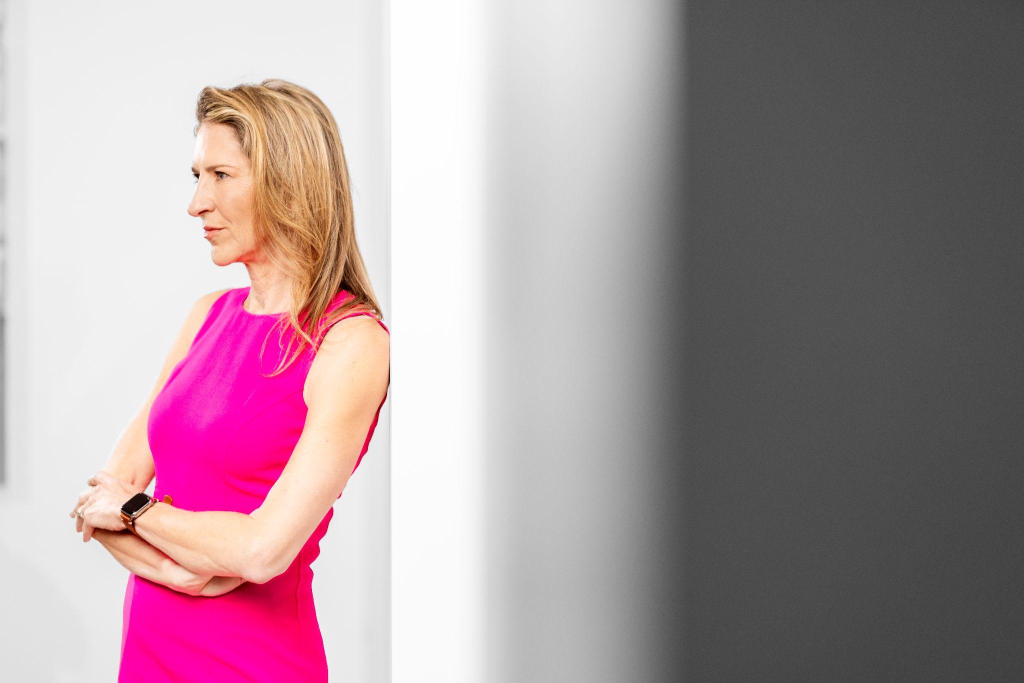 Plastic surgeon in pink dress offering guidance on replacing breast revision